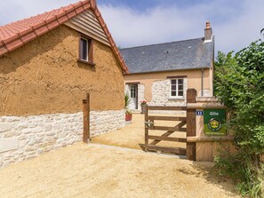 A rustic building with a stone wall, a wooden door, and a gate. - Charming renovated Normandy house with garden and terrace (Saint-Pellerin (Manche))