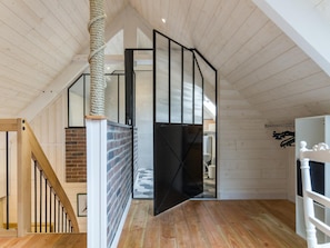 Une pièce de style loft avec un escalier en bois, un mur en briques et une cloison noire.