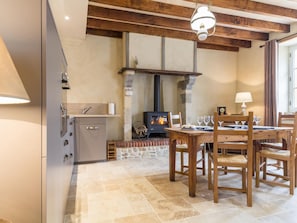 Une cuisine chaleureuse avec une cheminée en pierre, une table à manger en bois et un four moderne.