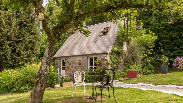 A stone house with a sloped roof, surrounded by lush greenery and a well-maintained lawn. - Charming house in the valley for 2, nature and tranquility (Beauficel)