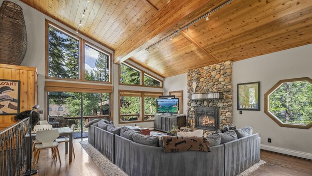 A spacious living area with a stone fireplace, large windows, and a cozy seating arrangement. - Artist’s Haven – Stylish Dollar Point Home with Hot Tub Near Skylandia Beach (Tahoe City)