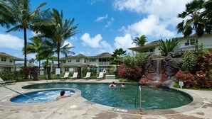 A pool area with a hot tub, lounge chairs, and a waterfall feature. - 3br Plantation at Princeville! AC, fitness center, hot tub,, garage, more! (Princeville)