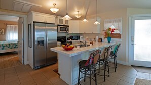 A modern kitchen with a central island, stainless steel appliances, pendant lighting, and a view to the outside. - 3br Plantation at Princeville! AC, fitness center, hot tub,, garage, more! (Princeville)