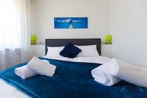 A hotel room with a bed, a painting of a lighthouse, and two bedside lamps. - Hotel Berlin (Schwetzingen)