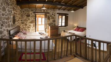 Un dormitorio rústico con paredes de piedra, una cama de madera, un aparador y una ventana.