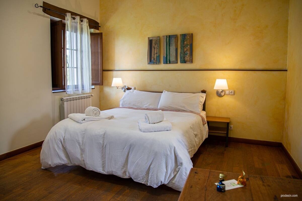 Ett hotellrum med en stor säng, två sänglampor, ett element och konstverk på väggen.