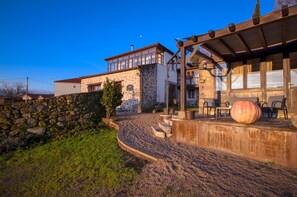 A stone building with a wooden porch and a large pumpkin on the steps.