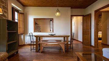 A dining area with a wooden table and chairs, a hanging light fixture, and a mirror on the wall.