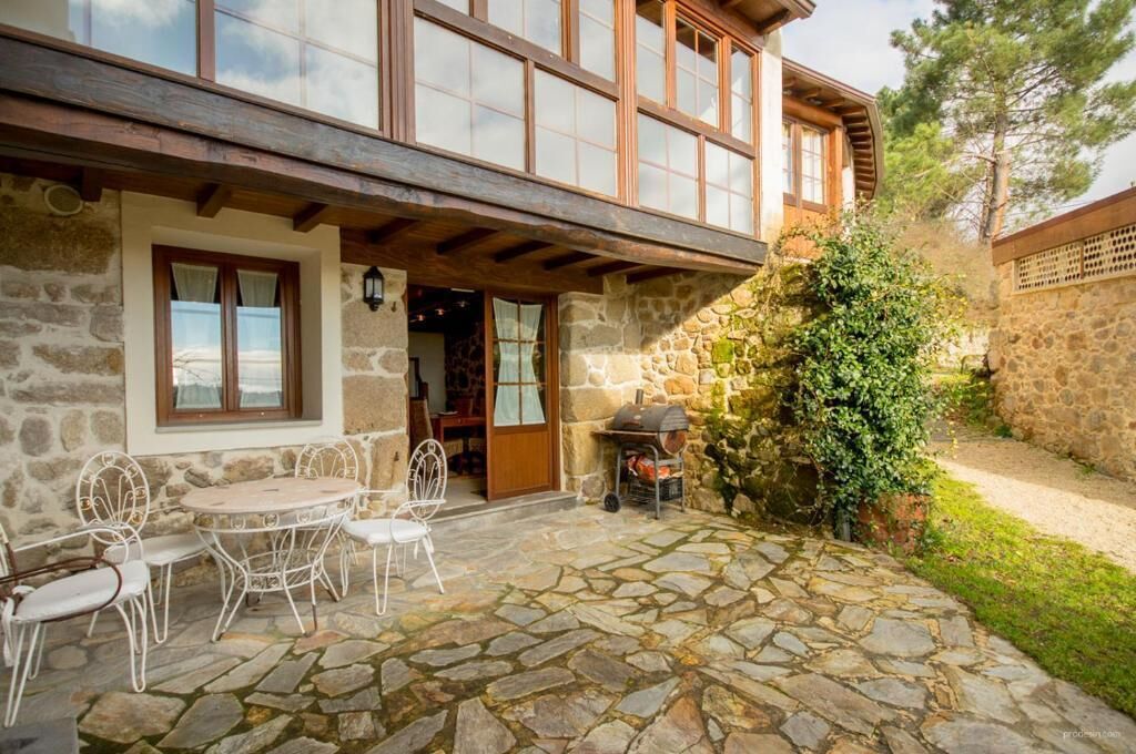 A stone building with a balcony, a stone patio with outdoor furniture, and a wooden door.