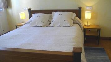 A neatly made bed with two pillows, two bedside lamps, and a wooden headboard.