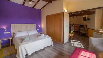 A bedroom with a bed, a wooden wardrobe, a small table, and a chair.