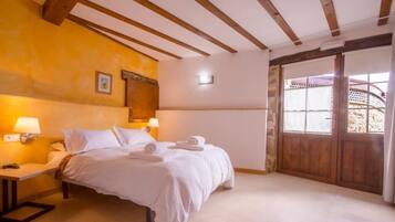 A hotel room with a bed, bedside lamps, a wooden door, and a view through the door.