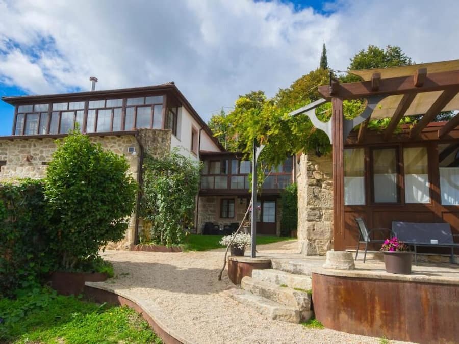 Un edificio de piedra con una terraza de madera y una pérgola.