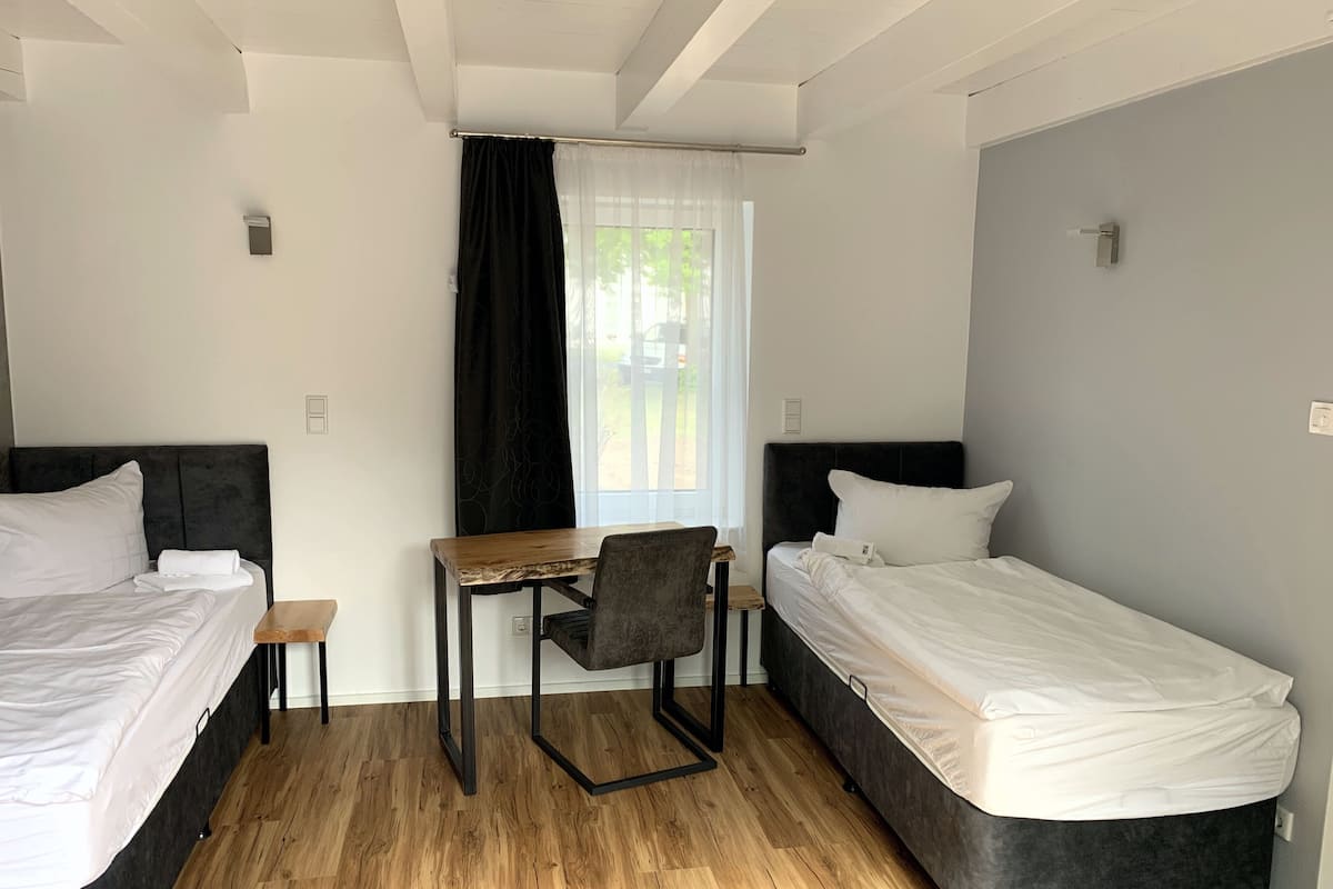 Ein Zimmer mit zwei Betten, einem Schreibtisch und einem Stuhl.