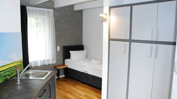 Pieni huone, jossa on sänky, pieni keittokomero ja vaatekaappi.