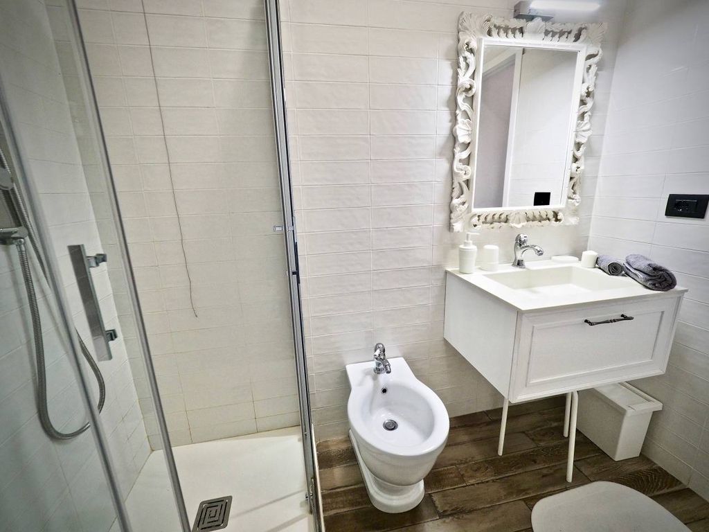 A bathroom with a shower, bidet, sink, and mirror.