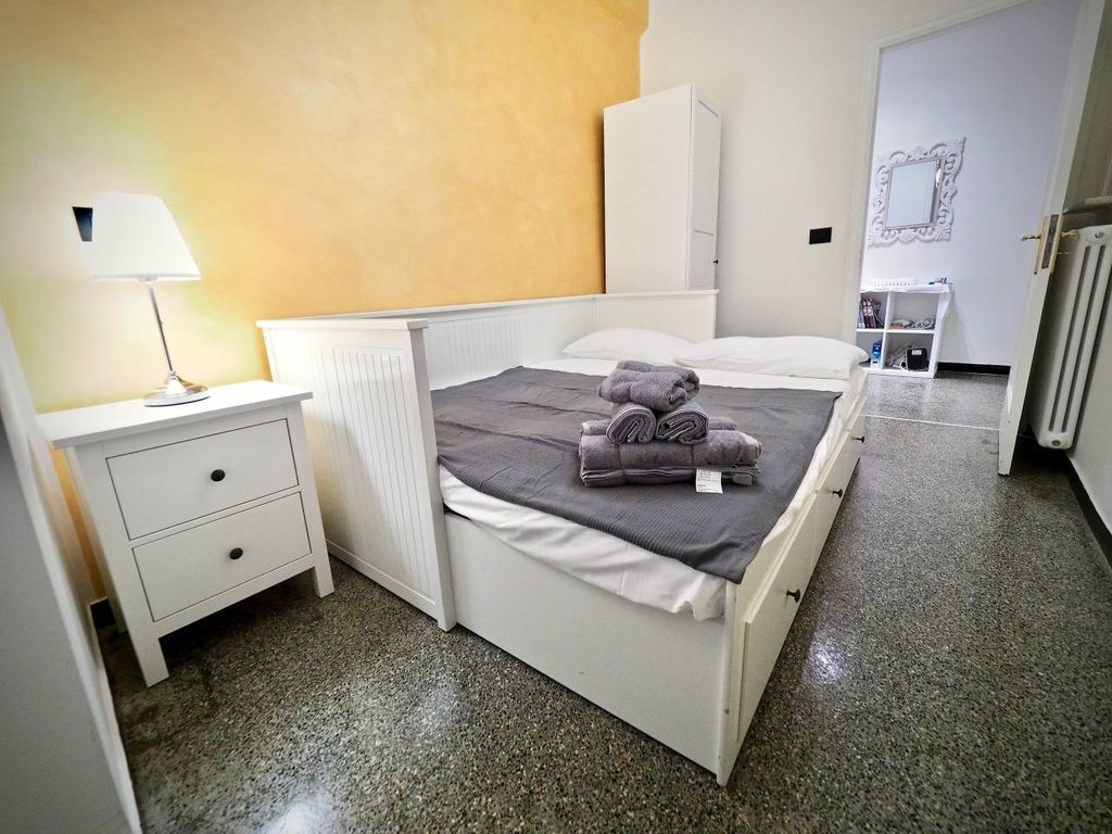 A bedroom with a bed, a nightstand, a radiator, and a wardrobe.