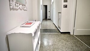 Um corredor com uma toucador branca, um espelho e uma porta no final.