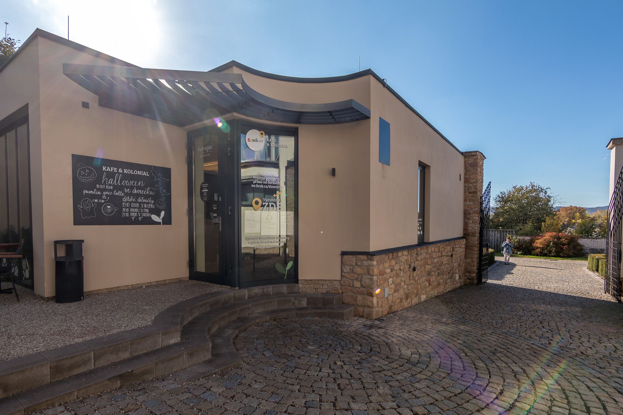 A building with a curved roof, a glass door, and a signboard.