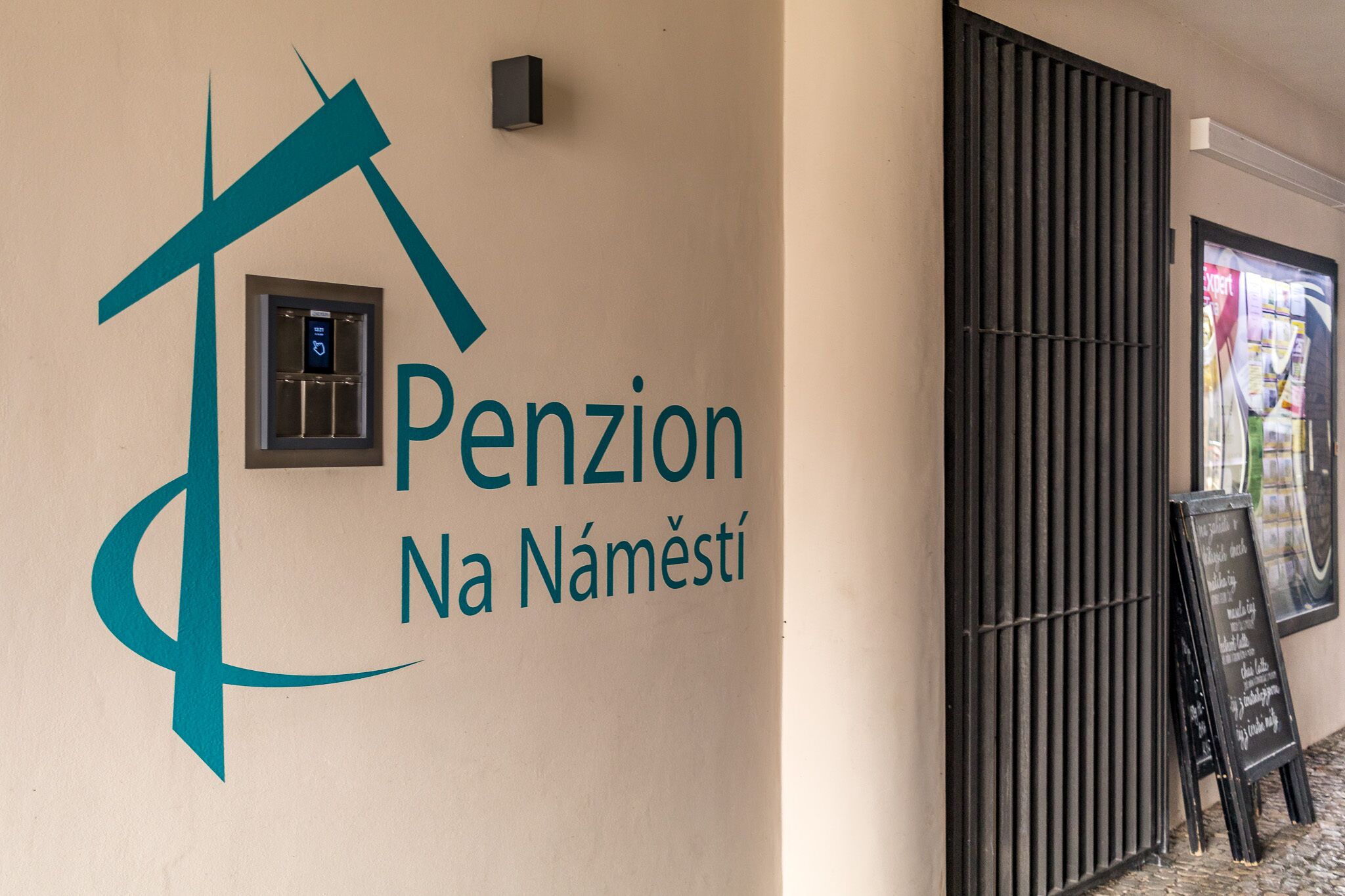 A wall with a logo and the name "Penzion Na Náměstí".