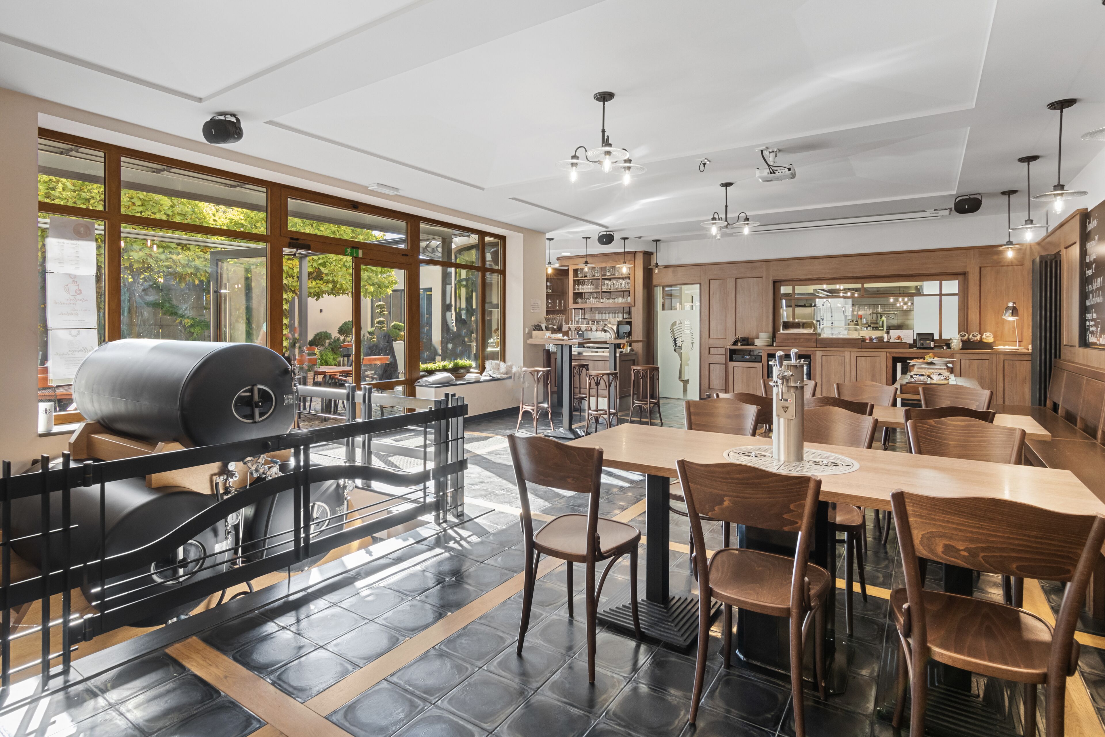 Un restaurante moderno con un amplio comedor, cocina al fondo y grandes ventanales.
