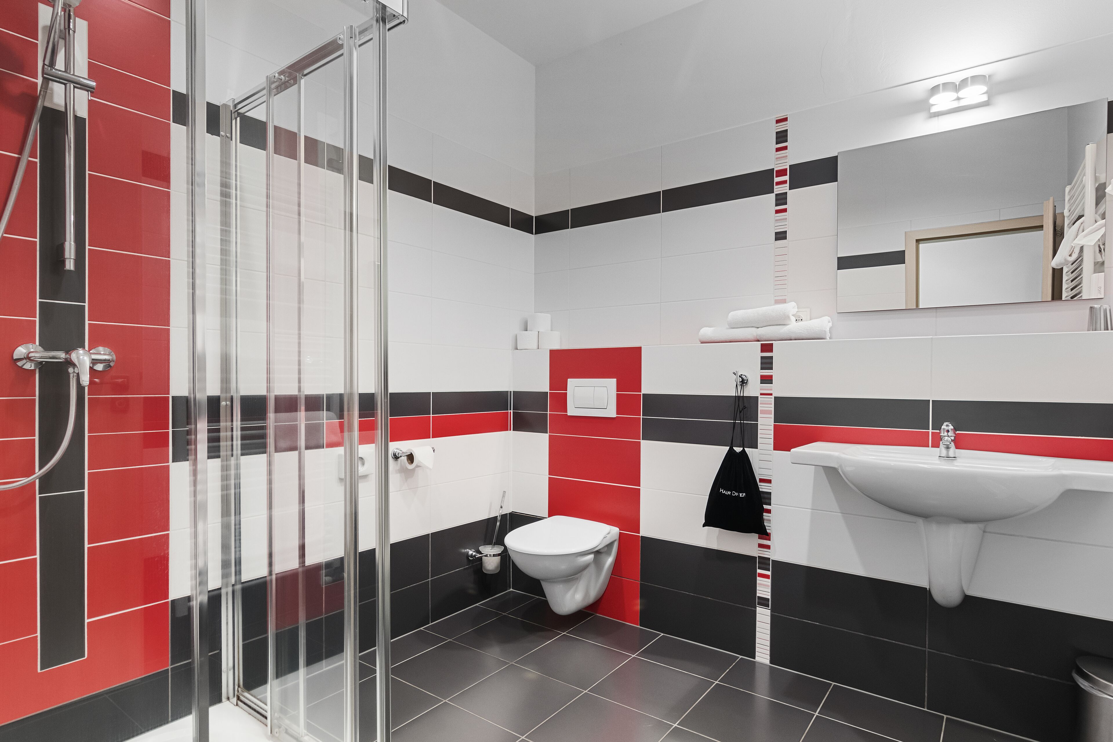 Un baño moderno con cabina de ducha de vidrio, un lavamanos blanco y un inodoro.