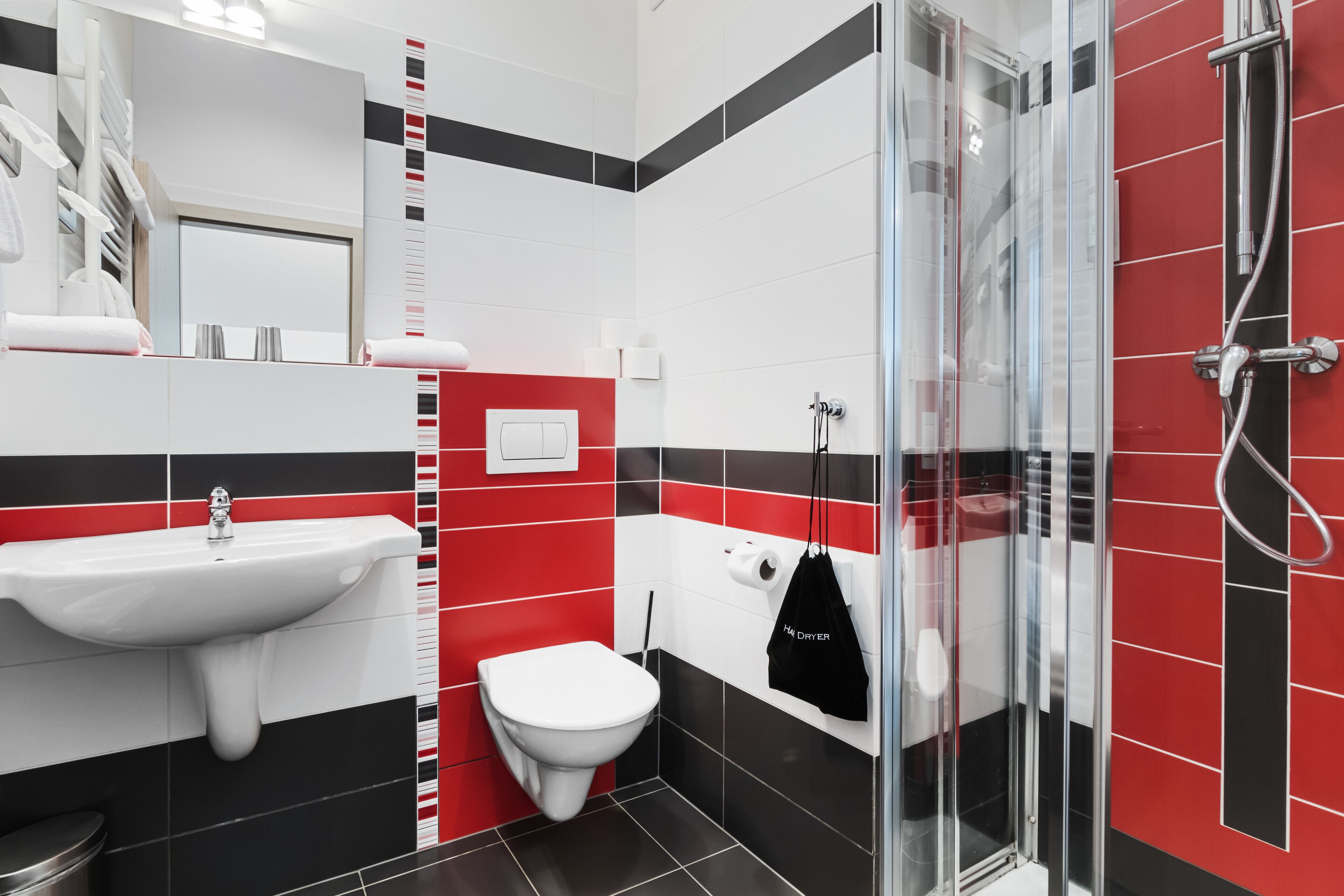 Une salle de bain moderne avec une douche à l’italienne en verre, un lavabo blanc et des toilettes.