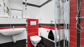 Une salle de bain moderne avec une douche à l’italienne en verre, un lavabo blanc et des toilettes.