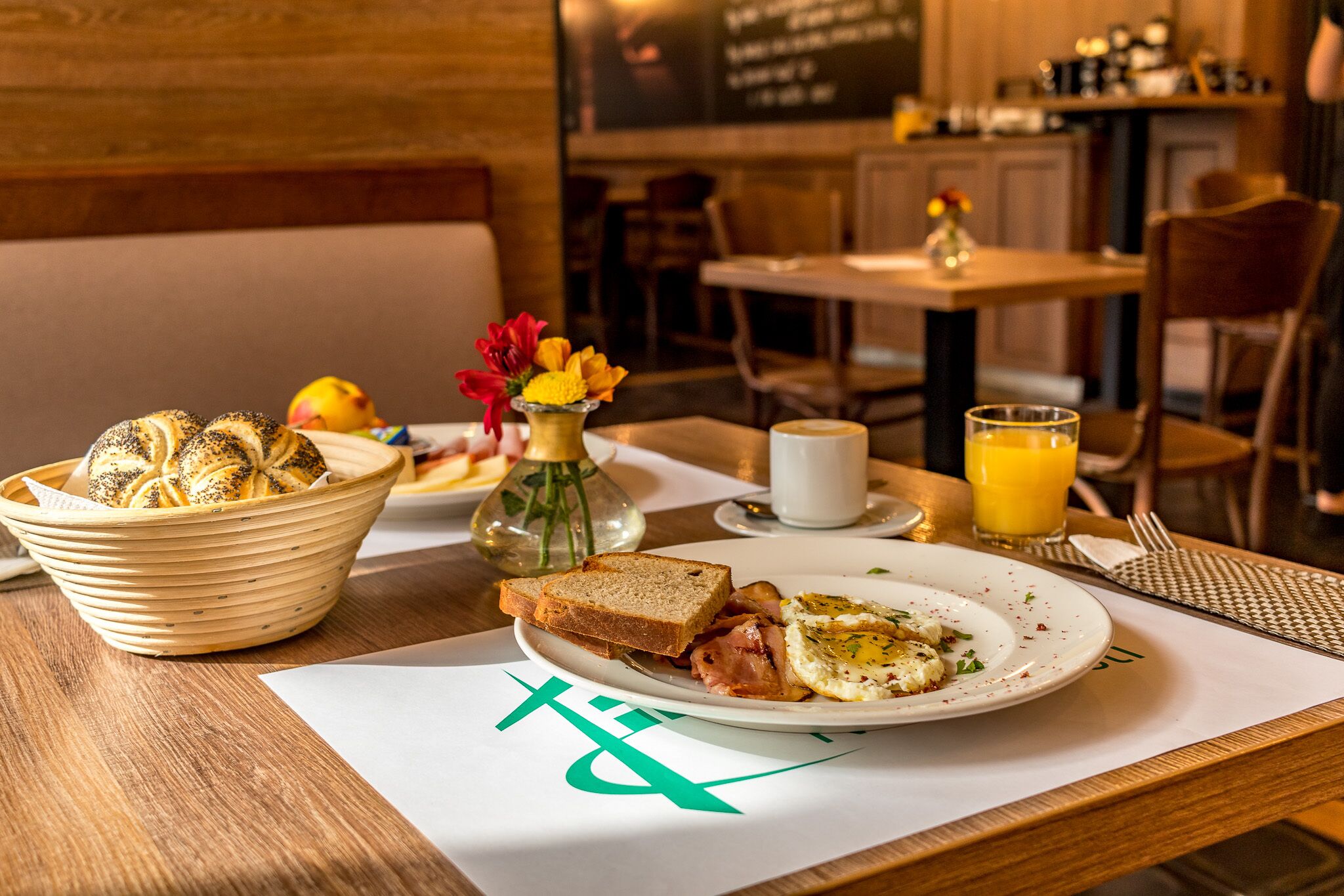 A breakfast setting with bread, eggs, and a glass of orange juice on a table.