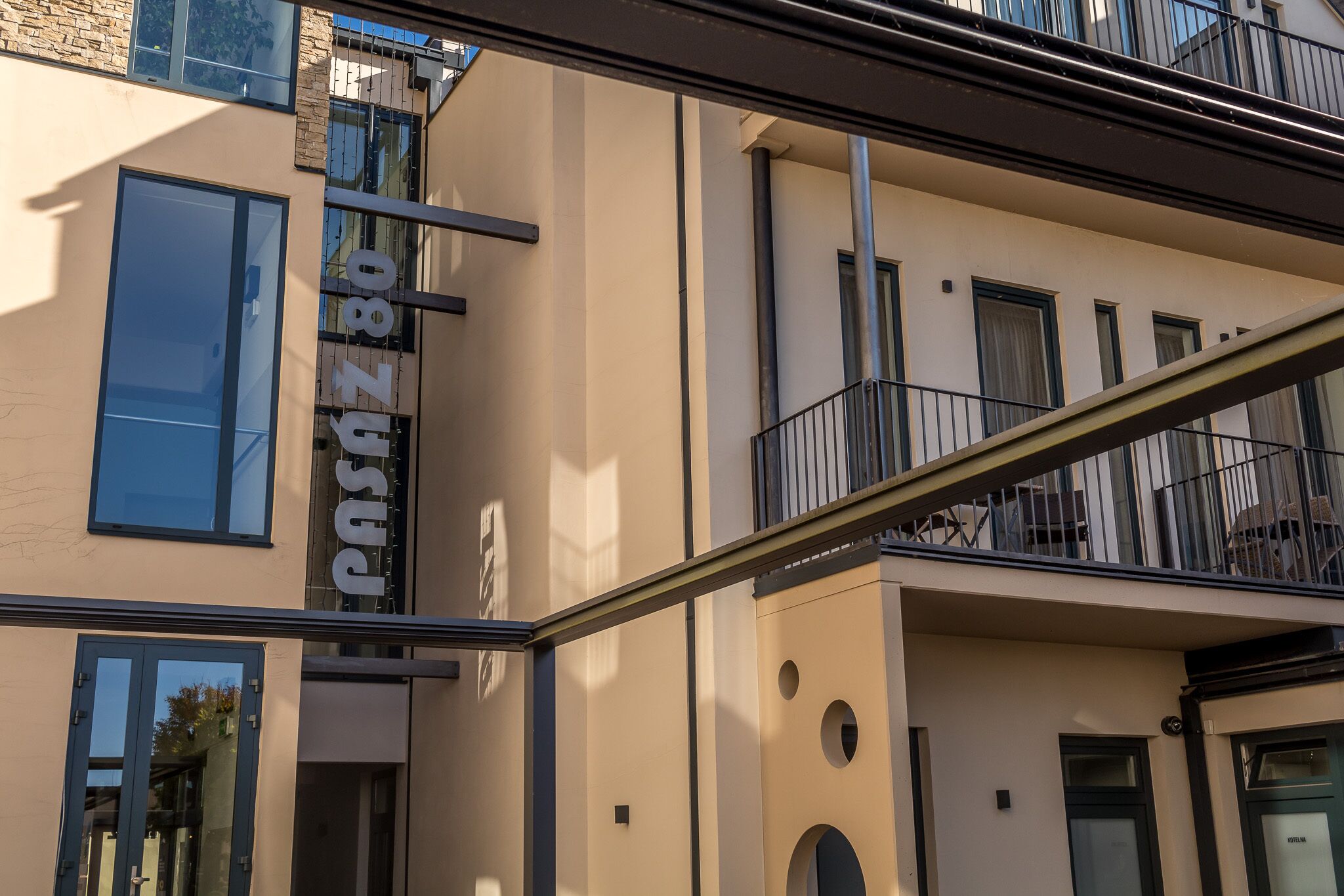 Ein modernes Gebäude mit einer beigefarbenen Fassade, großen Fenstern und Balkonen.