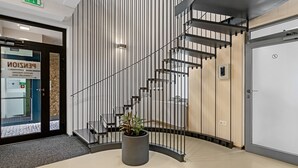 Un intérieur moderne avec un escalier en colimaçon, un comptoir d’accueil et une plante en pot.