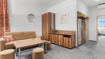 Una sala moderna con un sofá, una mesa de centro, otomanas y un aparador de madera.