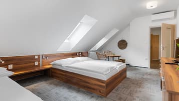 A modern bedroom with a sloped ceiling, a wooden bed frame, a small desk, and a chair.