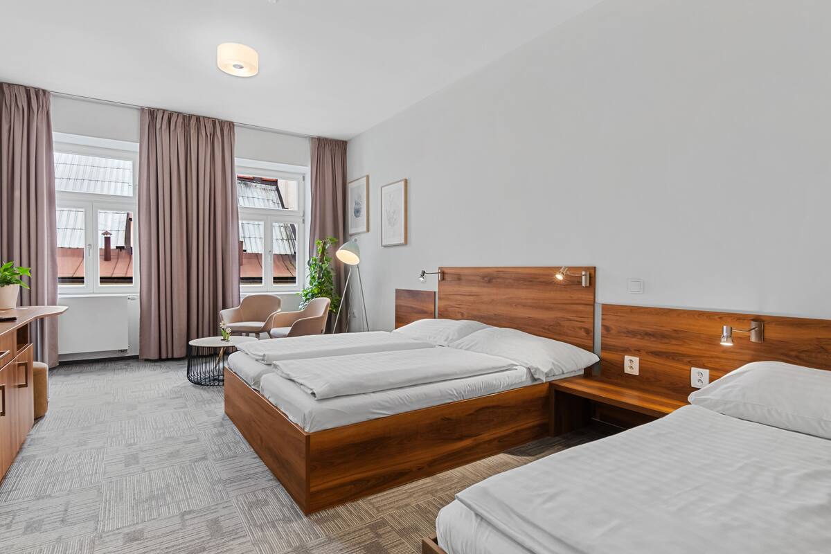 Ein Hotelzimmer mit zwei Betten, einem Schreibtisch, einem Stuhl und einem Fenster mit Vorhängen.
