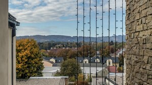 Un balcon donnant sur une ville, avec un mur en pierre et un ciel dégagé.