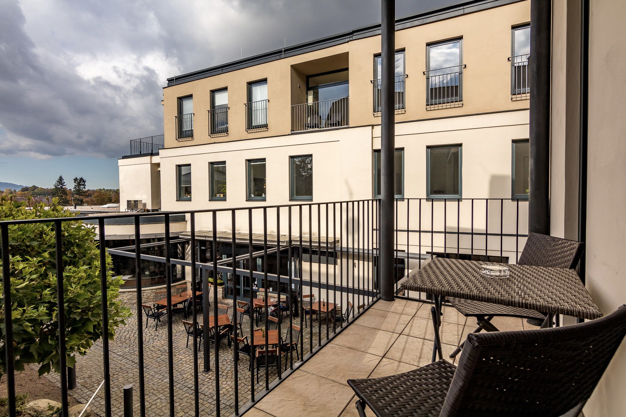 Un bâtiment moderne doté d’un balcon aménagé avec des sièges pour l’extérieur et offrant une vue sur le paysage environnant.