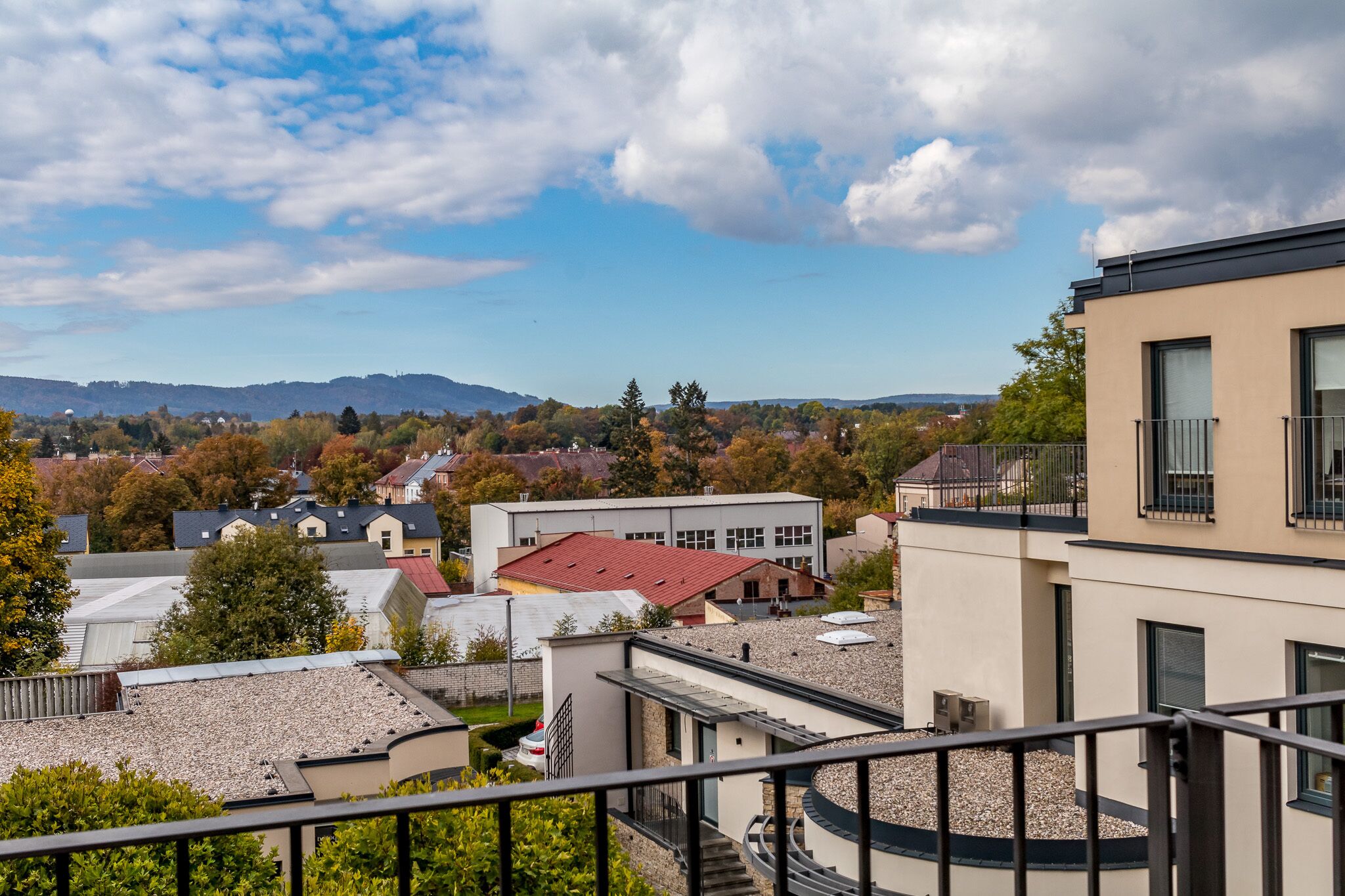 A residential area with modern buildings, a clear sky, and distant mountains.