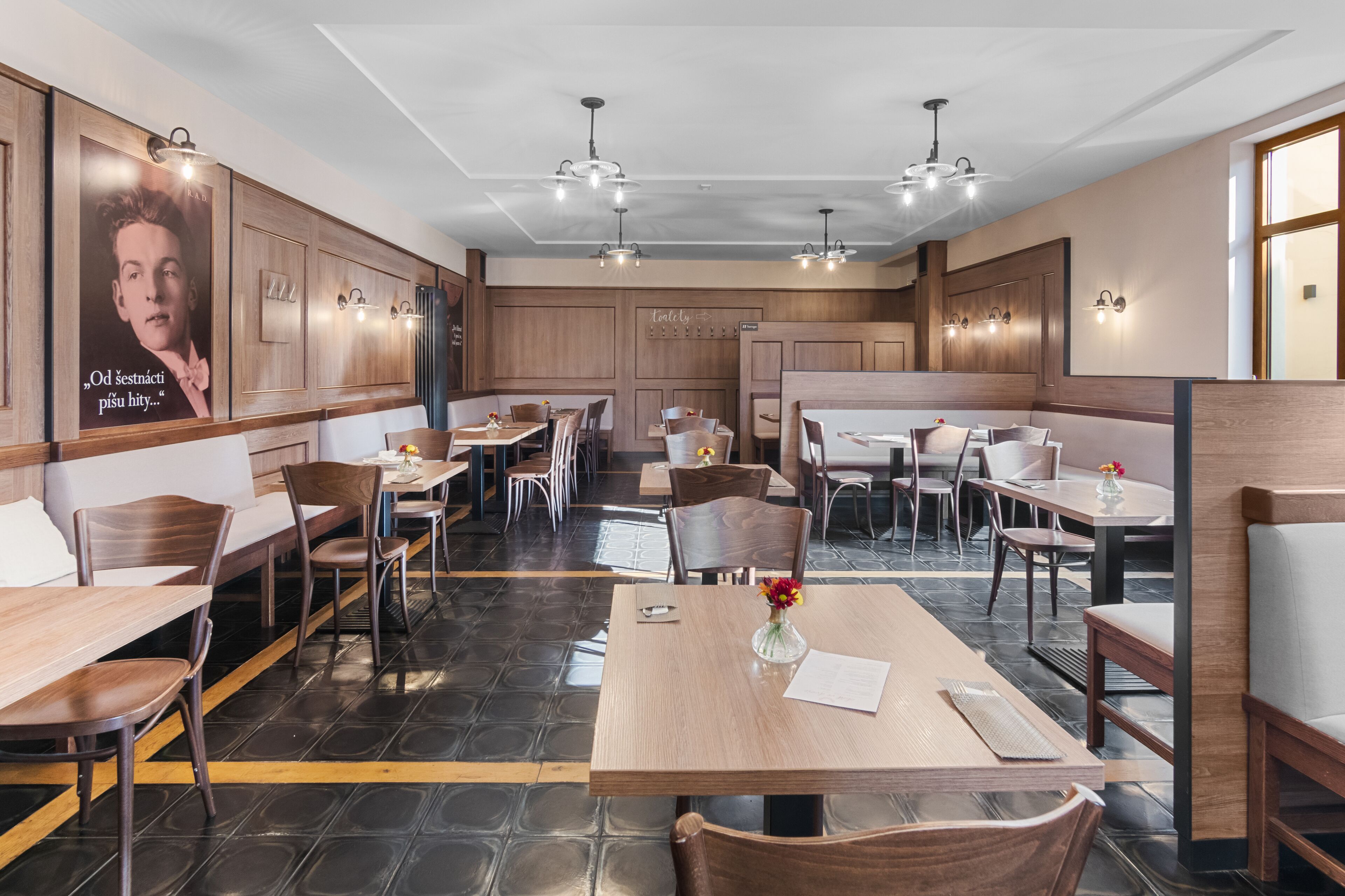 Un restaurant avec des banquettes, des tables en bois et des luminaires modernes.