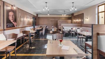 A restaurant with wooden booths, tables, and modern lighting fixtures.