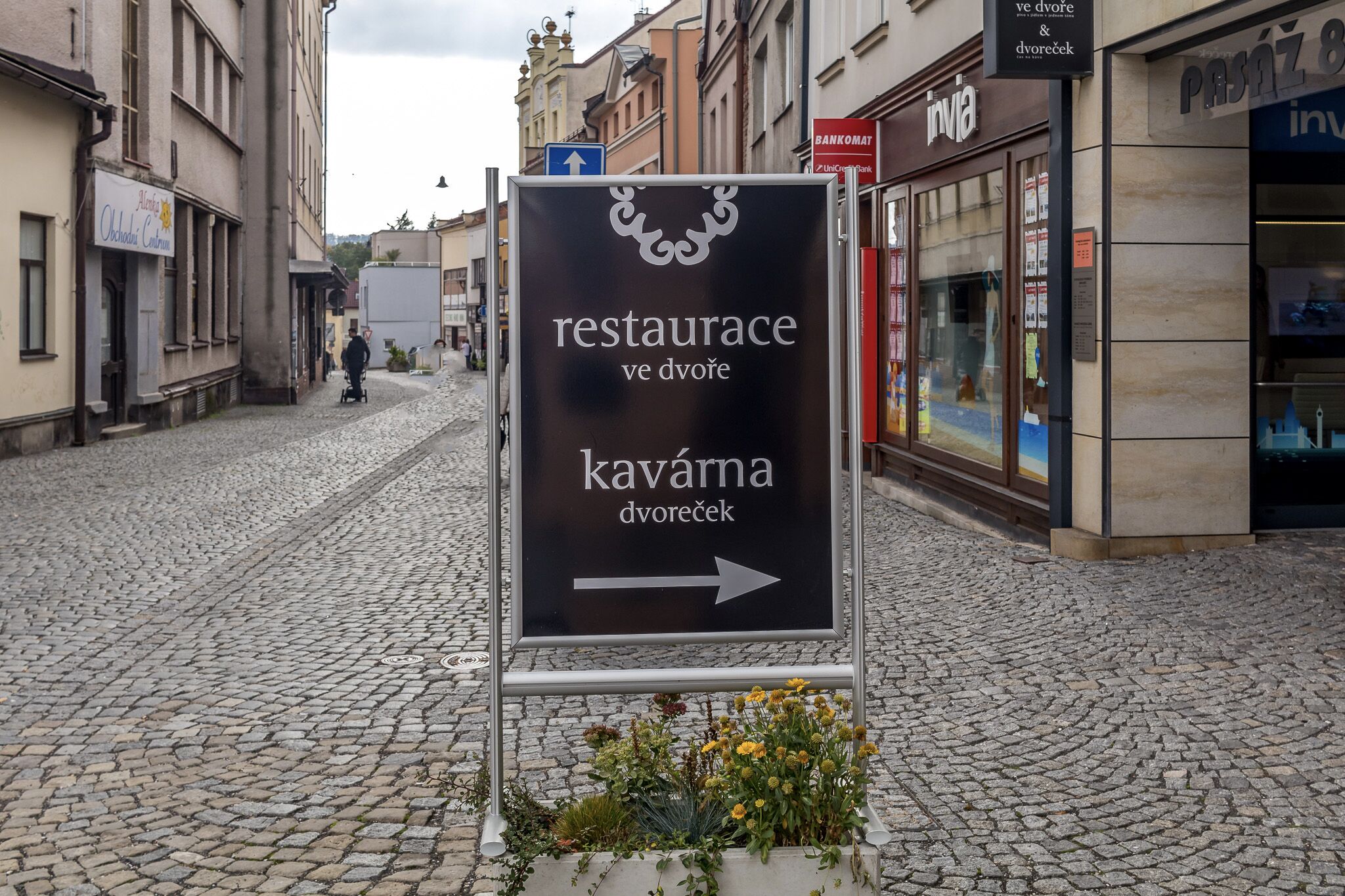 A cobblestone street with a sign pointing to a restaurant and a divorcee cafe.
