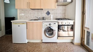 Een kleine keuken met houten kastjes, een wasmachine, een vaatwasser en een kookplaat.