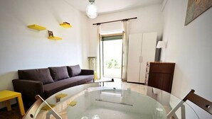 Een woonkamer met een ronde glazen tafel, een bank en een houten vloer.