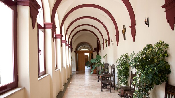 A corridor with arched ceilings, a tiled floor, and wooden furniture. - Hospedería Nuestra Señora del Carmen (Caravaca de la Cruz)