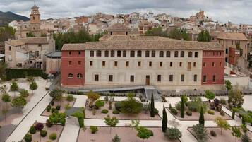 A historic building with a symmetrical facade, a central courtyard with pathways, and a surrounding urban landscape.