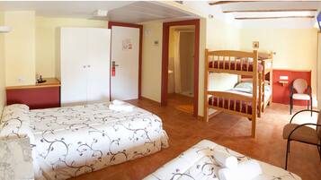Una camera d'albergo con un letto, una scrivania, una sedia, un letto a castello e un angolo doccia.