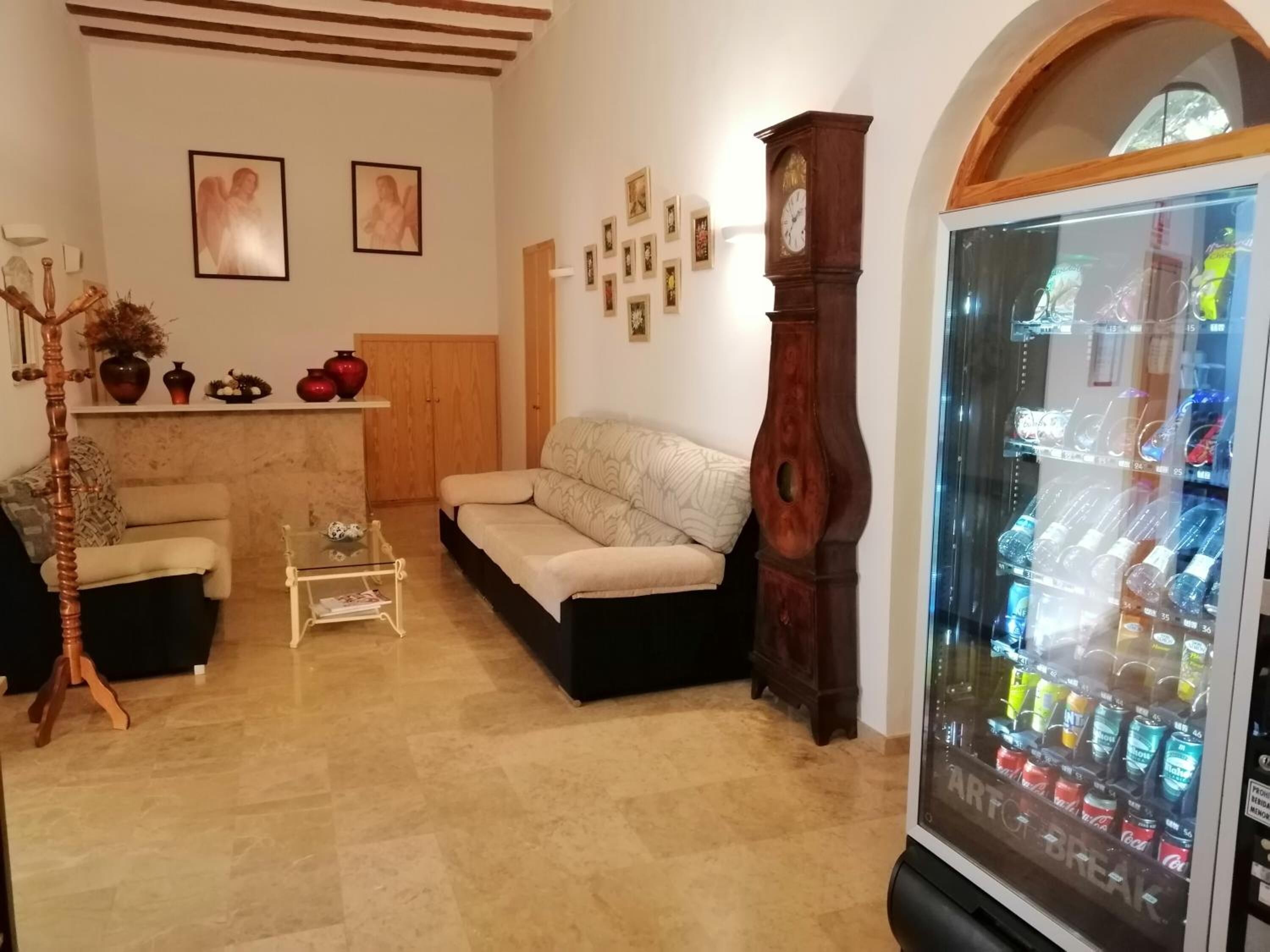 Una sala de estar con un sofá, una mesa de centro, un reloj y una máquina expendedora.