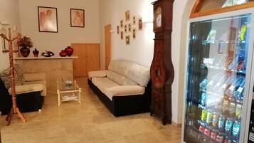 Una sala de estar con un sofá, una mesa de centro, un reloj y una máquina expendedora.