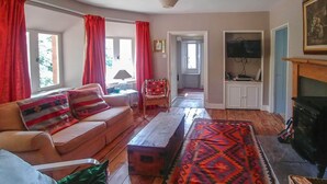 A living room with a sofa, a coffee table, a patterned rug, a fireplace, and a television. - Bamff Ecotourism (Blairgowrie)