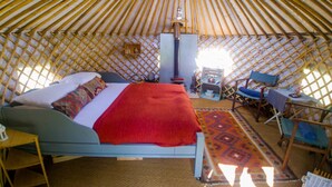 A yurt with a bed, a table, chairs, and a stove. - Bamff Ecotourism (Blairgowrie)