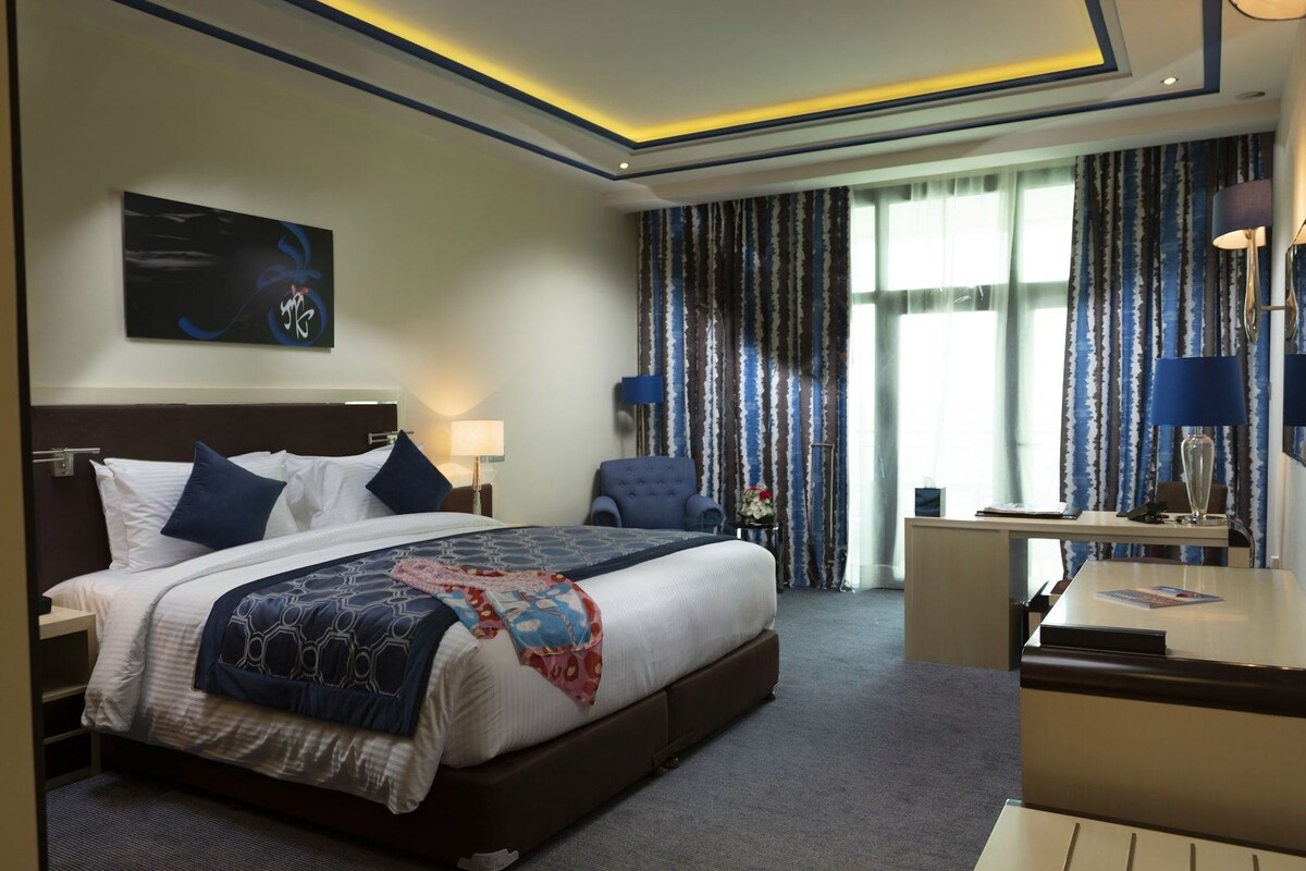Une chambre d’hôtel avec un grand lit, des tables de chevet, un bureau et une chaise.